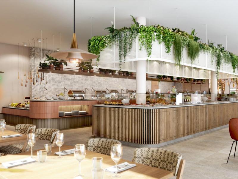 Modern hotel restaurant with long counter, pendant lamps, and lush green decor
