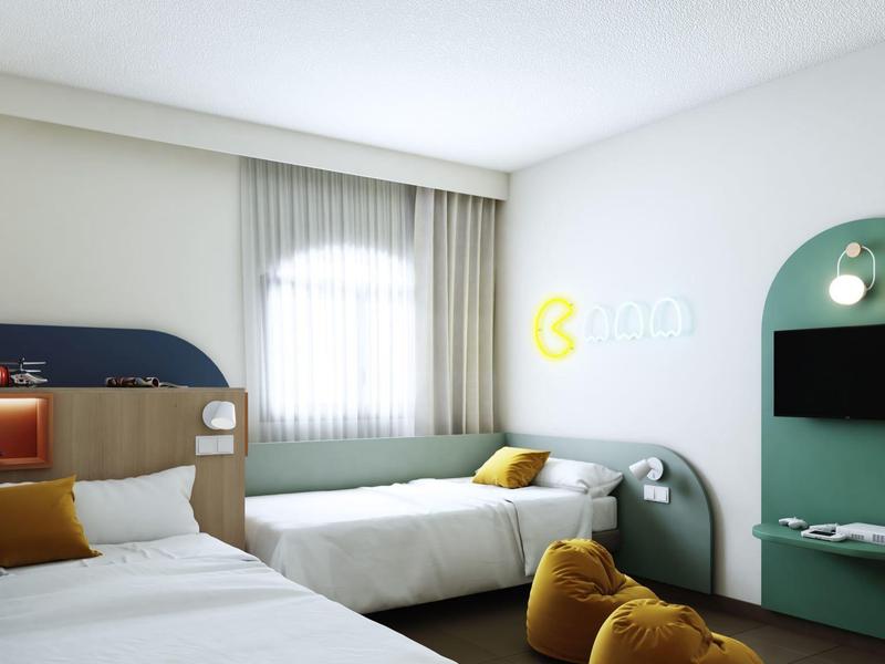 Modern hotel room with two beds, TV, and cozy decor in soft colors.