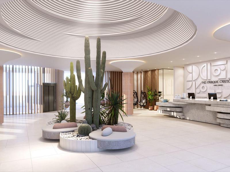 Bright hotel lobby with round seating and large cactus plant in the center.