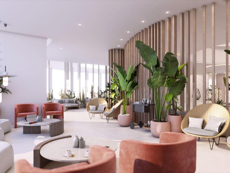 Elegant lounge with comfortable chairs, plants, and modern room dividers in hotel setting.