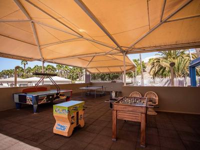 Covered recreation area with table football and air hockey in a tropical hotel setting.