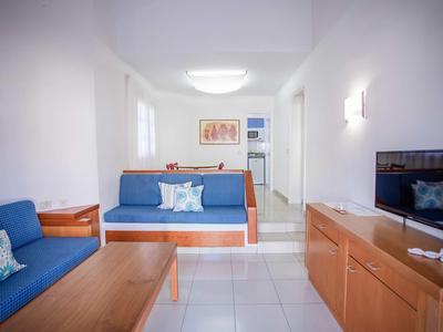 Bright living room with blue sofa, wooden furniture, and TV in a modern holiday apartment.