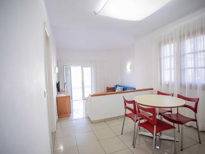 Bright living room with dining area, red chairs, and balcony in a hotel room.