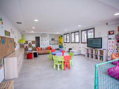 Bright, colorful children’s playroom with small tables, chairs, and bean bags in a hotel.