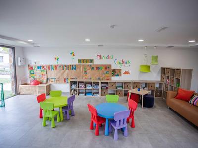 Colorful children's playroom with small tables, chairs, and shelves filled with toys.