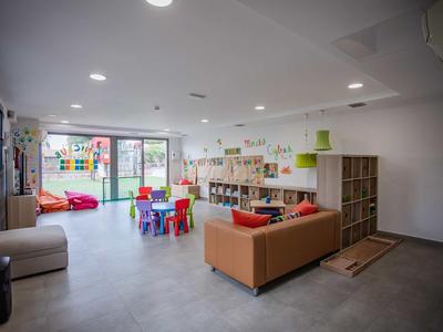 Bright and colorful kids' play area with seating, bookshelves, and access to the outdoor space.