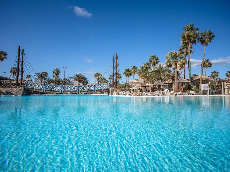 Large pool with clear blue water and palm trees on a sunny day.