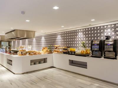 Buffet moderne avec pâtisseries et machines à café dans un espace lumineux et élégant.