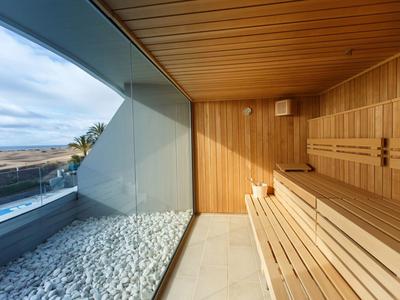 Sauna en bois avec vue panoramique sur la mer à travers une large baie vitrée.
