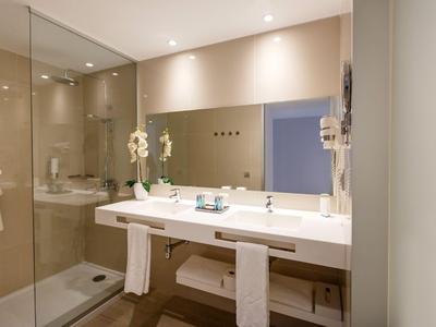 Miroir de salle de bain moderne avec grande double vasque et douche dans la chambre d'hôtel.