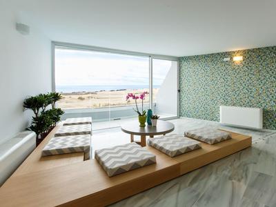 Minimalist seating area with low wooden table and beach and sea view.