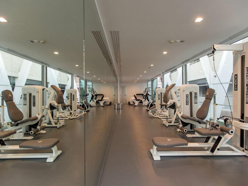 Salle de sport moderne avec machines alignées et lumière naturelle abondante.