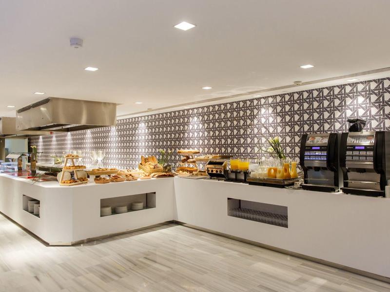 Buffet moderne avec pâtisseries et machines à café dans un espace lumineux et élégant.