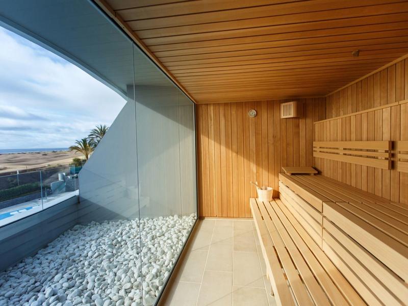Sauna en bois avec vue panoramique sur la mer à travers une large baie vitrée.