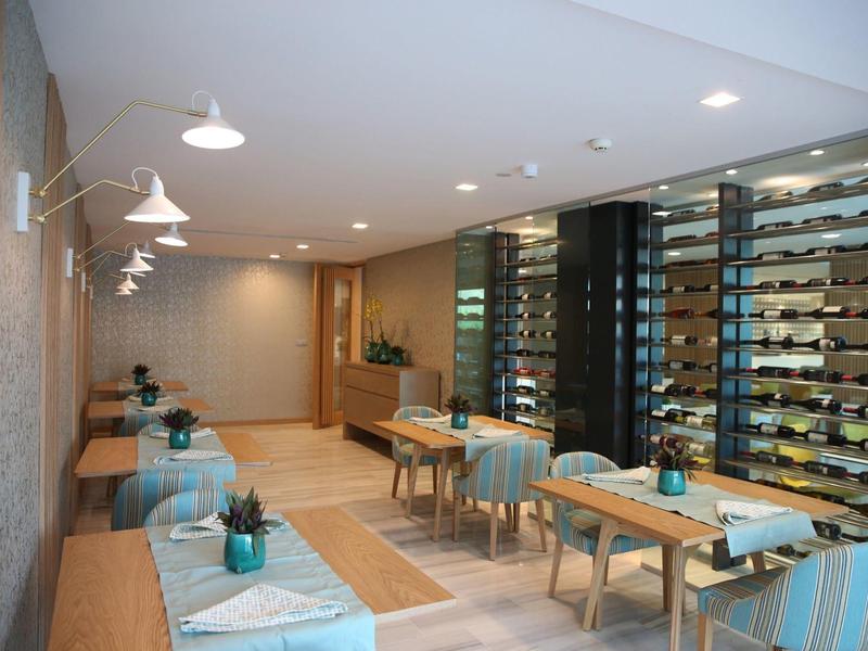 Salle à manger d'hôtel moderne avec tables élégantes et grand mur vitré exposant des bouteilles.