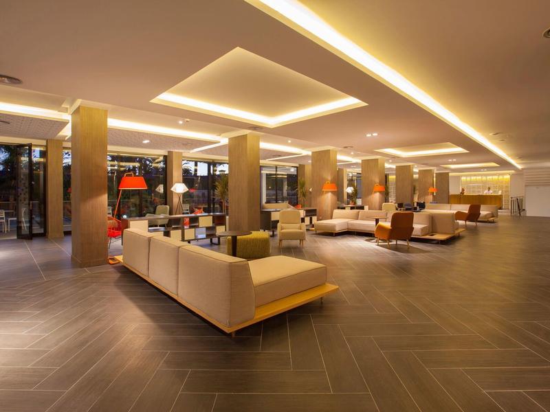 Przestronny hol hotelowy z nowoczesnym oświetleniem i wygodnymi miejscami do siedzenia.
