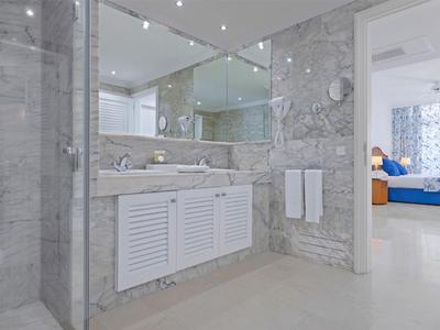 Moderne Badezimmer mit weißem Waschbecken und Steinwand neben einem offenen Schlafzimmer.