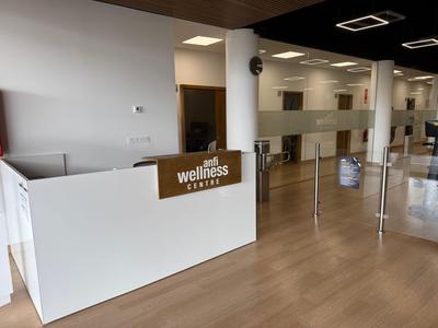 Moderner Empfangsbereich eines Wellnesscenters mit weißer Theke und Holzboden.