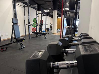 Moderne Hotel-Fitnessstudio mit Hanteln, Gewichten und Trainingsstationen auf schwarzem Boden.