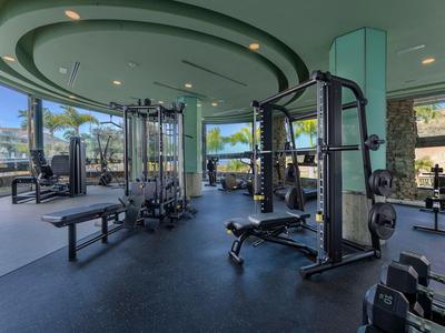 Modernes Fitnessstudio mit Geräten und Panoramafenstern mit Blick auf Palmen.