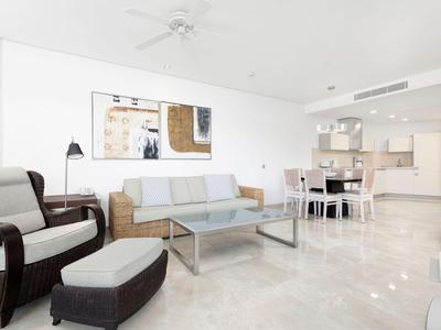 Modern eingerichtetes Wohnzimmer mit Sofa, Sessel, Couchtisch und Essbereich in hellem Raum.