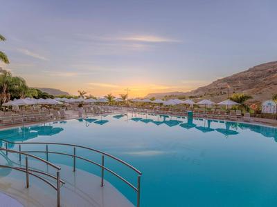Großes Außenpool mit Bergen im Hintergrund und Sonnenuntergangsstimmung.