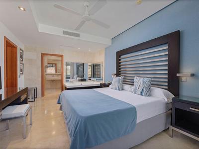 Modernes Hotelzimmer mit Doppelbett, Schreibtisch, Fernseher und Badezimmer im Hintergrund.