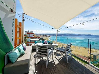 Terrace with seating area overlooking sea, beach, and sky under a sunshade