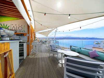 Modern balcony with kitchenette, seating area, and view of the sea and mountains in the background.