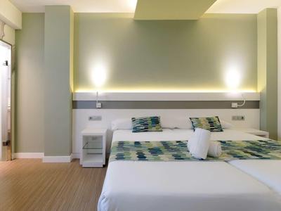 Helles, modernes Schlafzimmer mit Doppelbett, Holzfußboden, grünen Wänden und LED-Beleuchtung.