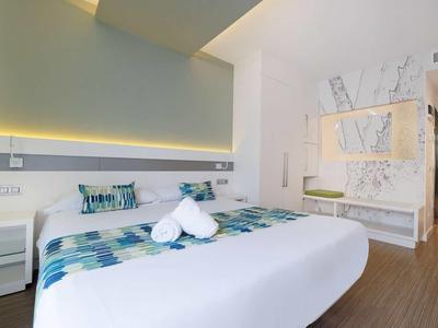 Modernes Schlafzimmer mit großem Bett, Holzfußboden und minimalistischer weißer Einrichtung.