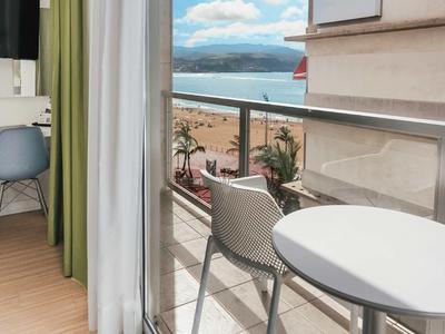 Balkon mit weißem runden Tisch, Stühlen und Meerblick bei bewölktem Himmel.