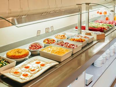 Buffet mit verschiedenen warmen Speisen in weißen Schalen, darunter Eier, Gemüse und Aufläufe.