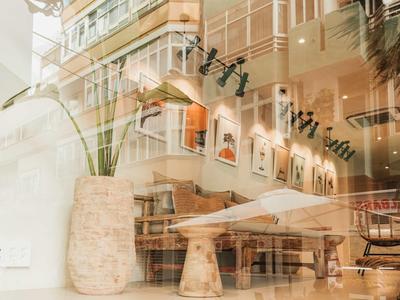 Modern eingerichteter Raum mit Holzmöbeln, großer Pflanze und warmem Licht hinter Glasfront.