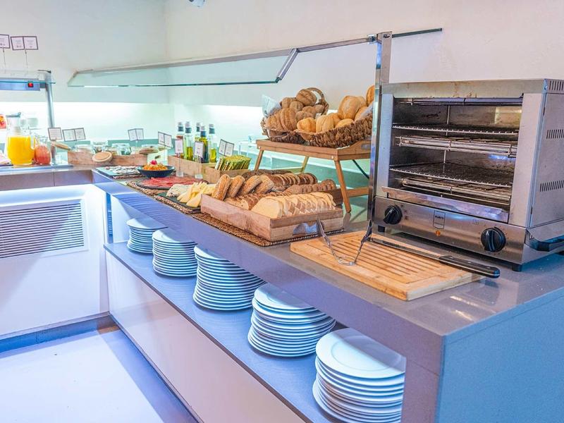 Buffet mit verschiedenen Brotsorten, Tellern und Toaster in heller, moderner Küche.