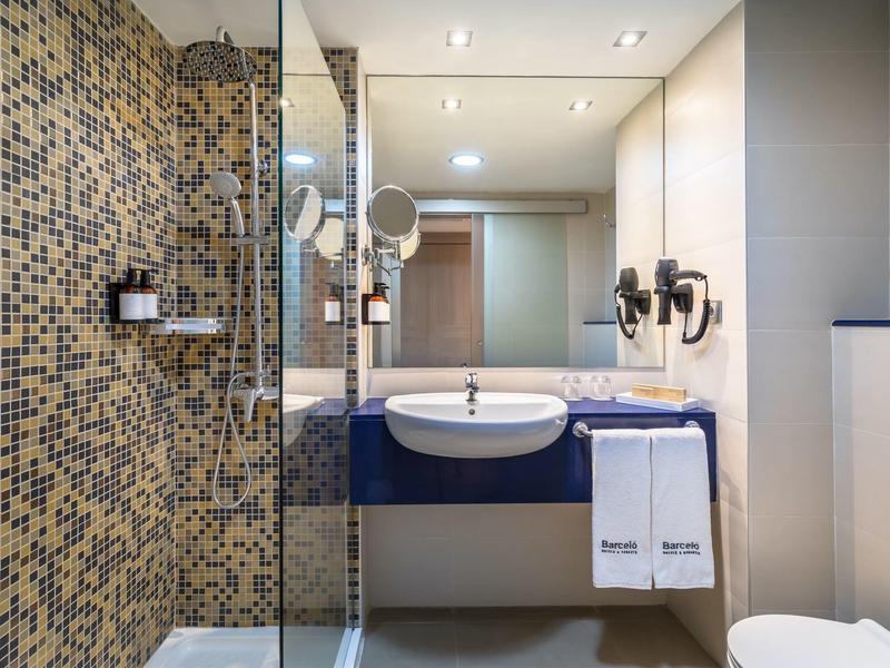 Modern bathroom with shower cabin, sink, mirror, and toilet in a hotel room.