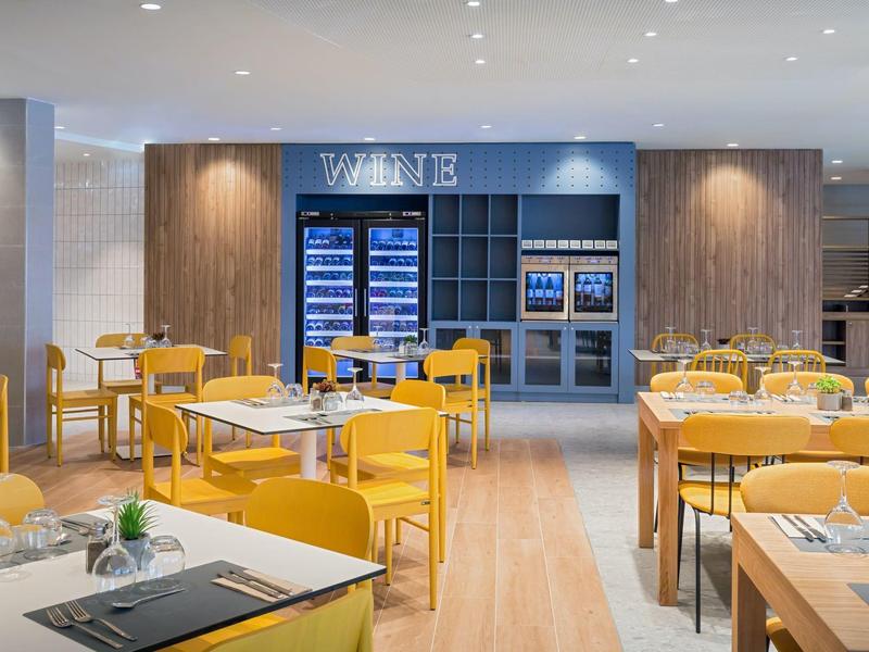 Bright dining area with yellow chairs and a well-stocked wine rack in the background.