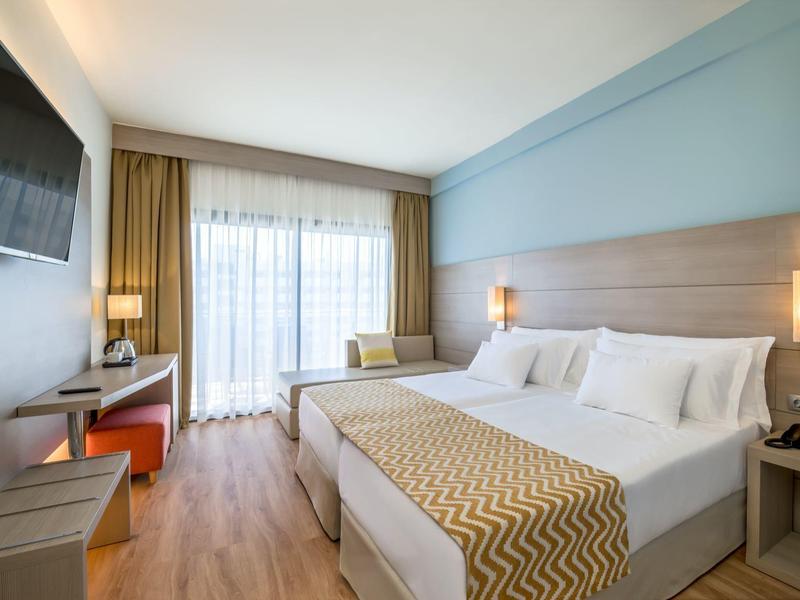 Modern hotel room with double bed, desk, and balcony