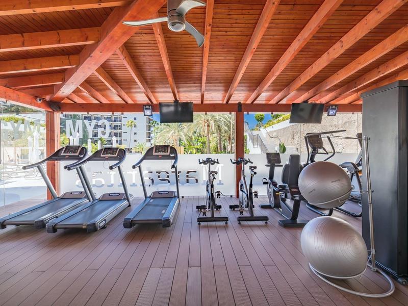 Modern gym with treadmills, exercise bikes, and gym balls under wooden ceilings.