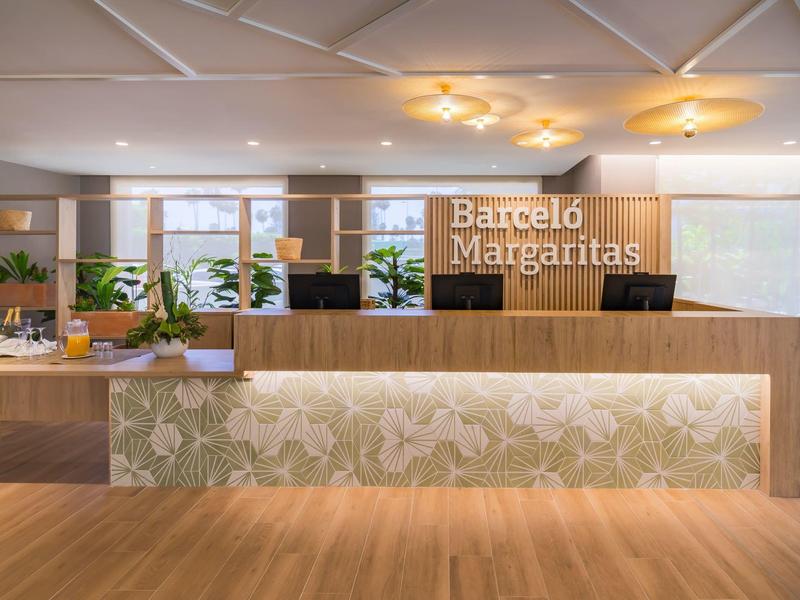 Modern hotel reception with wooden counter and decorative lighting design.