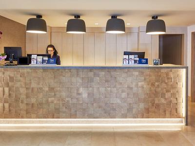 Reception d'hotel moderna con receptionist e caldi dettagli in legno.