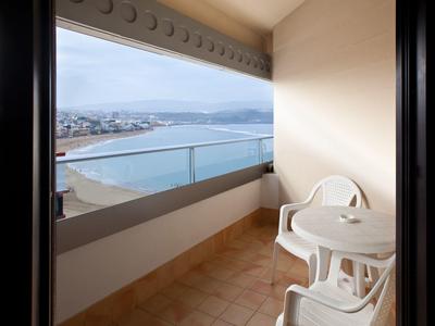 Balcone con due sedie bianche e tavolo con vista sul mare e sulla costa.