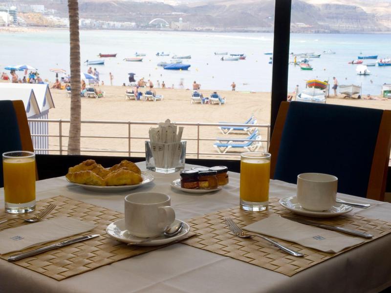 Tavolo per la colazione vicino a una spiaggia con vista su barche e mare