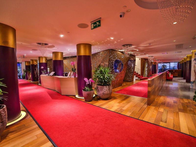 Elegante hall d'hotel con moquette rossa, colonne dorate e arredamento moderno