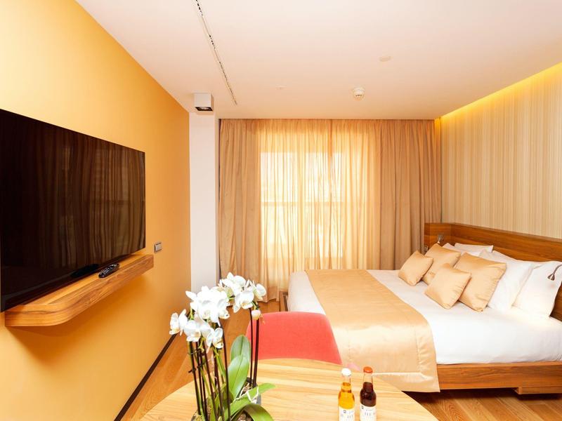 Camera d'hotel accogliente con letto matrimoniale, TV e illuminazione calda.