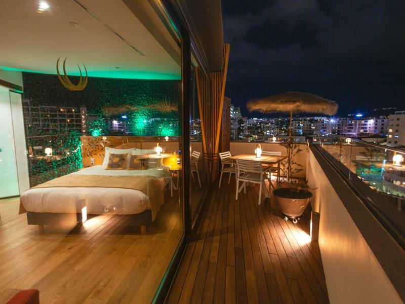 Terrazza moderna con posti a sedere e vista sulla città di notte.