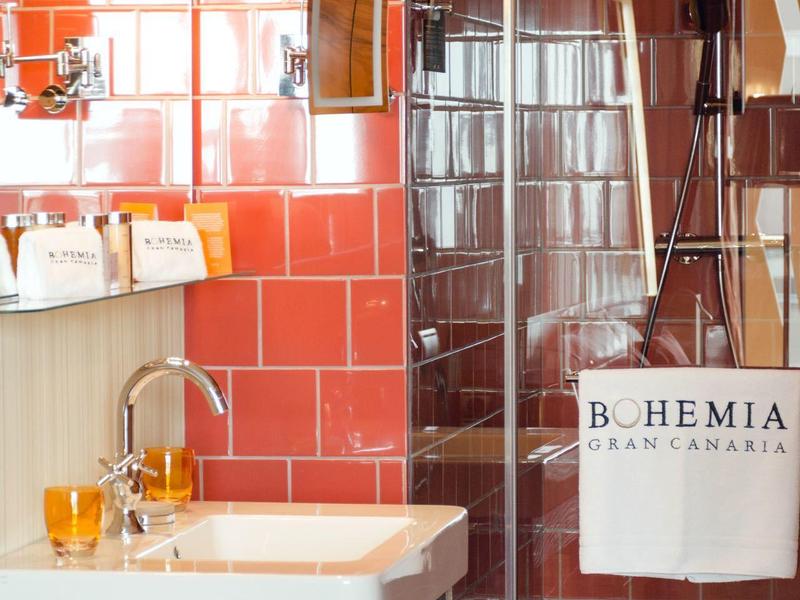 Bagno moderno con piastrelle rosse, doccia in vetro e asciugamani bianchi