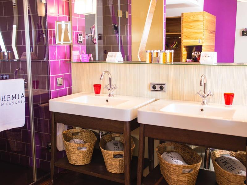 Bagno moderno con due lavandini, cesti e piastrelle viola.