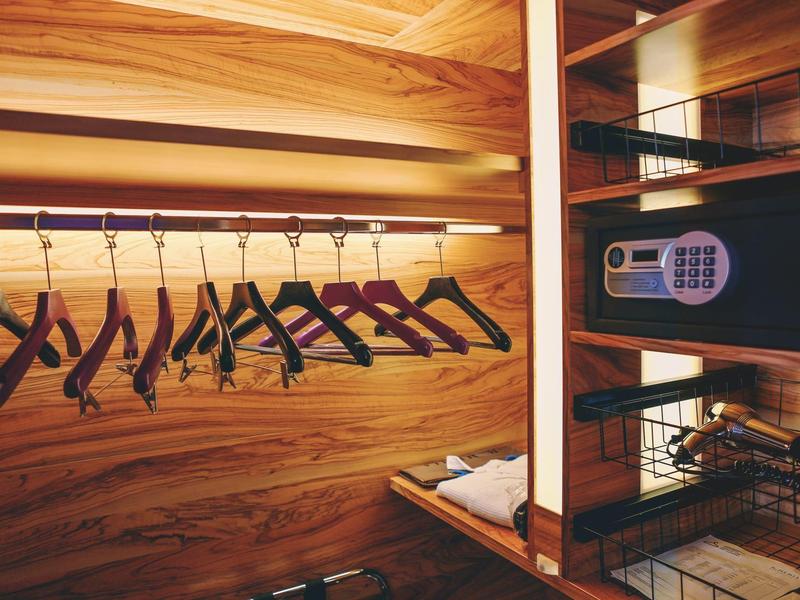 Guardaroba in legno con appendini neri e cassaforte elettronica sicura.