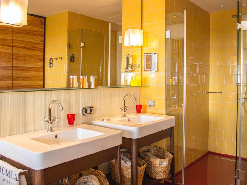 Bagno moderno con doppi lavabi, specchi e porta in vetro per la doccia.